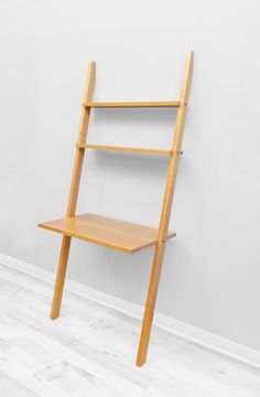 a wooden shelf sitting on top of a hard wood floor next to a white wall