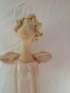 a ceramic sculpture of a woman's head in a glass vase on a white wall