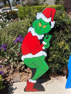 the grinch is standing in front of some bushes