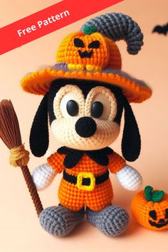 a crocheted mickey mouse with a pumpkin hat and broom sitting next to it