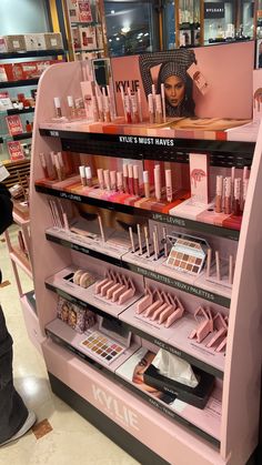 a display in a store filled with lots of pink cosmetics and makeup products on shelves