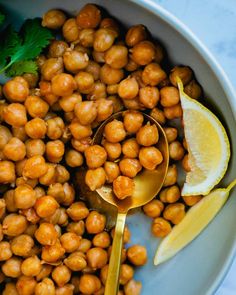 a bowl filled with chickpeas, lemon and parsley next to a spoon