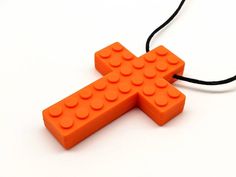 an orange lego cross necklace on a black cord