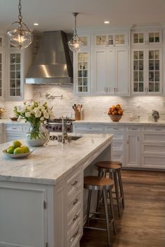 a large kitchen with white cabinets and marble counter tops, along with wooden flooring