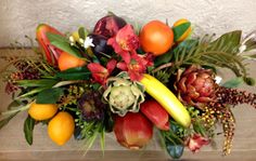 an arrangement of fruit and flowers on a table