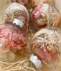 four glass ornaments with pink and white flowers in them