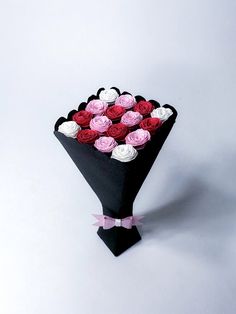 a bouquet of pink and red roses in a black paper wrapper on a white background