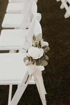 white folding chairs with flowers and greenery tied to the back are lined up in rows