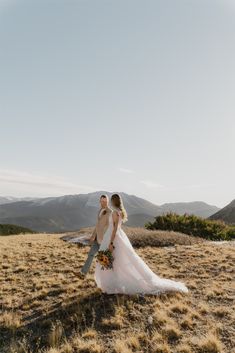 a bride and groom walking in the mountains