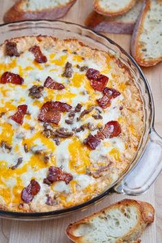 a casserole dish with bacon and cheese on it next to slices of bread