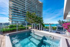 an outdoor hot tub on top of a building next to the ocean with flowers in front of it