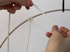 two hands are holding the end of a wire and pulling it up with one hand