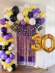 balloons and streamers decorate the entrance to an 80th birthday party in purple, gold and white