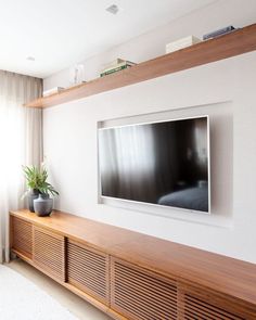 a large flat screen tv mounted to the side of a wooden shelf in a living room