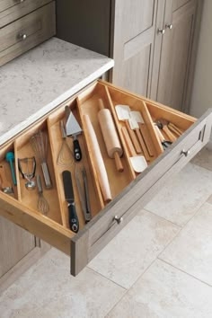 an open drawer with utensils and other kitchen items in it on the counter