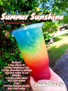 a hand holding up a colorful drink in front of some trees and bushes with the text summer sunshine on it