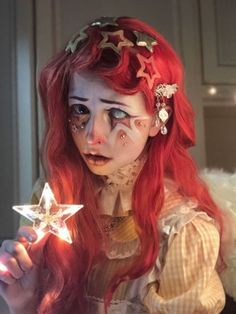 a woman with red hair and makeup holding a star