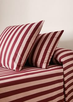 two red and white striped pillows sitting on top of a bed next to each other