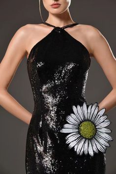 a woman wearing a black and white dress with a flower on the back of it