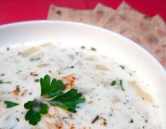 a white bowl filled with soup and garnished with parsley on crackers