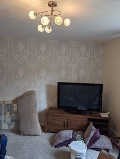 a living room filled with furniture and a flat screen tv on top of a wooden dresser