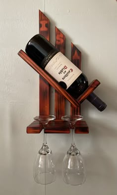 two wine glasses and a bottle on a wooden rack