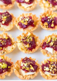 small pastries with cranberry sauce and pistachio toppings on a white tray