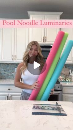 a woman holding three pool noodle luminaries in her hands