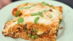 a white plate topped with lasagna covered in cheese and green onions on top of it