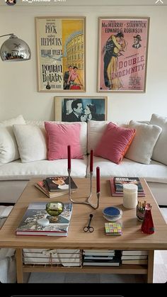 a living room with white couches and pink pillows on the coffee table in front of it