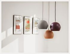 three different colored lamps hanging from the ceiling in a room with pictures on the wall