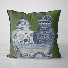 two blue and white vases sitting next to each other on a green pillow cover