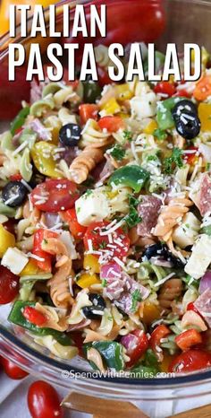 pasta salad in a glass bowl with tomatoes, olives and parmesan cheese