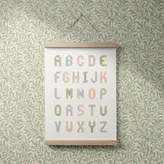 a cross stitch alphabet is hanging on the wall next to a green and white wallpaper