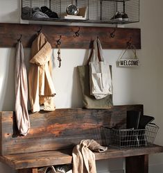 a wooden bench with baskets and bags hanging from it's hooks on the wall