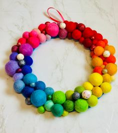 a multicolored wreath made out of pom - poms on a marble surface