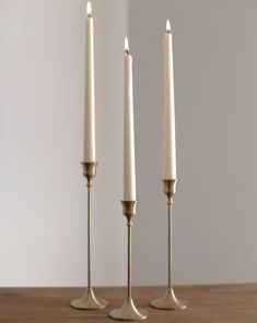 three white candles sitting on top of a wooden table