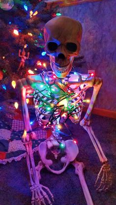 a skeleton sitting in front of a christmas tree with multicolored lights on it