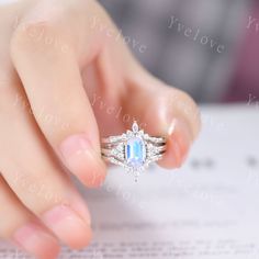 a woman's hand holding a ring with an oval shaped blue stone in it