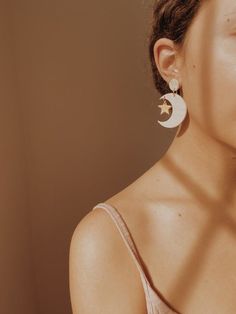 a woman wearing earrings with a star and moon on it