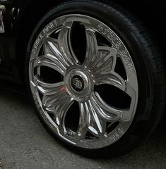 the front wheel of a black car with chrome spokes