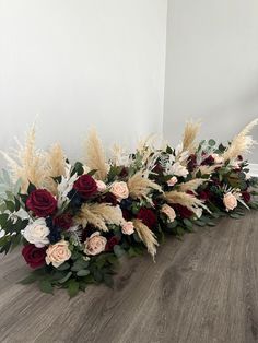 flowers and foliage arranged on the floor in a row with white, red and pink flowers