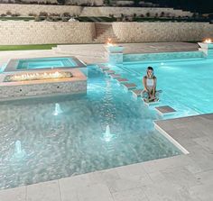 a woman is sitting in the middle of a swimming pool with steps leading up to it