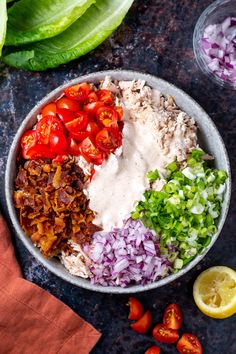 a bowl filled with meat, vegetables and sauce on top of a table next to lettuce