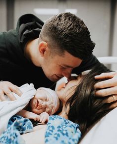 a man and woman kissing while holding their baby