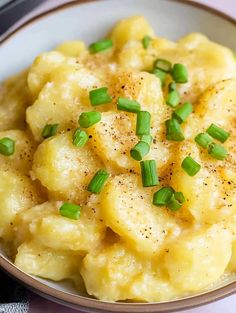 a bowl filled with macaroni and cheese topped with green onions