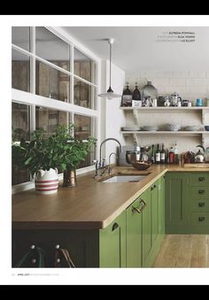 a kitchen with green cabinets and wooden counter tops, pots and pans on the shelves