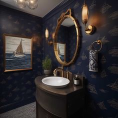 a bathroom with blue wallpaper, gold fixtures and an oval mirror on the wall