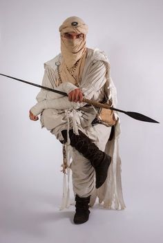 a man dressed up as a warrior with two swords in one hand and a mask on the other