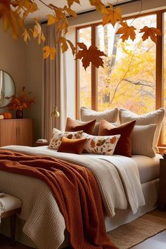 a bed sitting under a window covered in lots of fall colored leaves on top of it